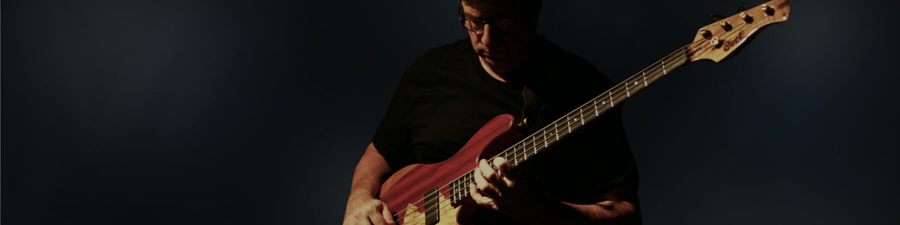 Jeff Berlin with his Cort Rithimic bass in a wide Cort artist banner.